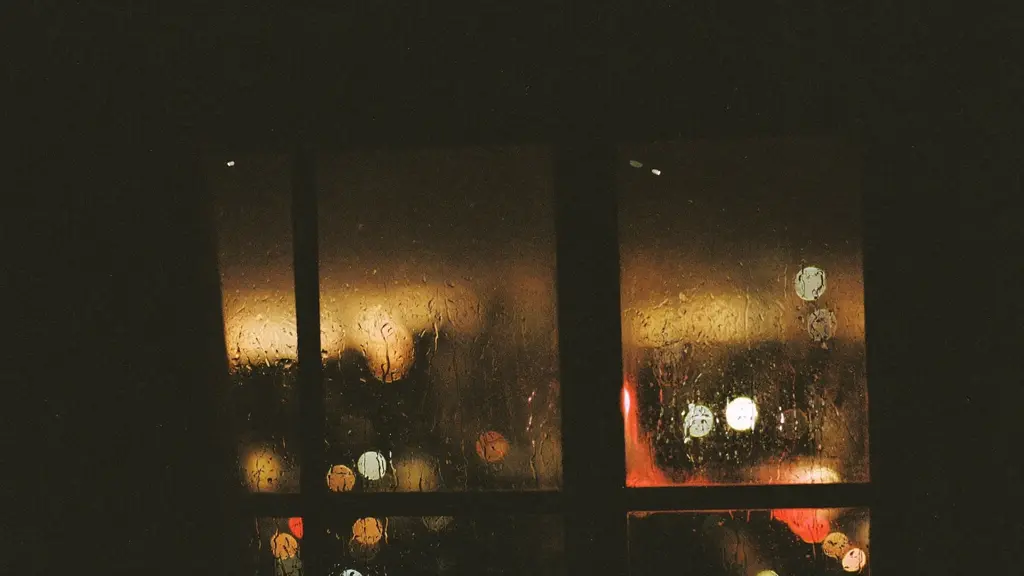 Rain on a dark window with warm city lights glowing beyond